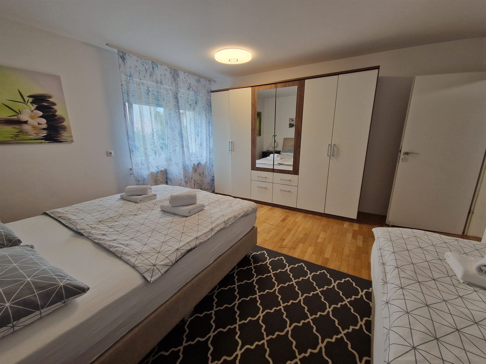 Una camera dell'appartamento n. 1 con letto matrimoniale, un'alta armadiatura a specchio e un tappeto a fantasia sul pavimento in legno